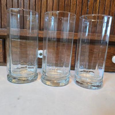 Two glass water pitchers and an assortment of miss-matched drinking glasses