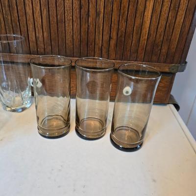 Two glass water pitchers and an assortment of miss-matched drinking glasses