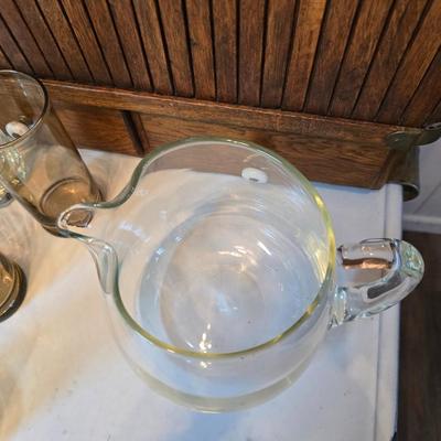 Two glass water pitchers and an assortment of miss-matched drinking glasses