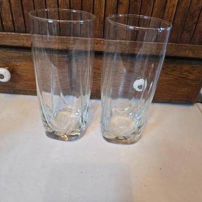 Two glass water pitchers and an assortment of miss-matched drinking glasses