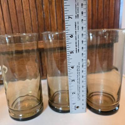 Two glass water pitchers and an assortment of miss-matched drinking glasses