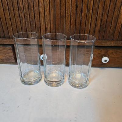 Two glass water pitchers and an assortment of miss-matched drinking glasses