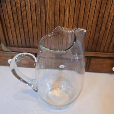 Two glass water pitchers and an assortment of miss-matched drinking glasses