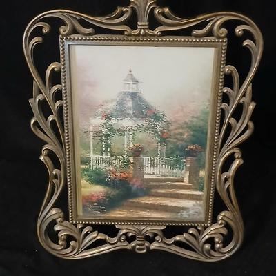 Framed print of the painting "The Hidden Gazebo" by Thomas Kinkade - Two ornate brass picture frames featuring a floral still...