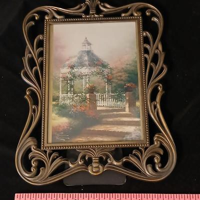 Framed print of the painting "The Hidden Gazebo" by Thomas Kinkade - Two ornate brass picture frames featuring a floral still...