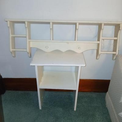Small white table with a shelf and a wall shelf unit with many cubbies