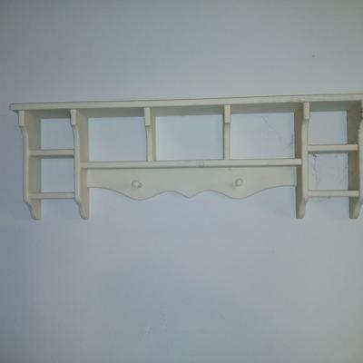 Small white table with a shelf and a wall shelf unit with many cubbies