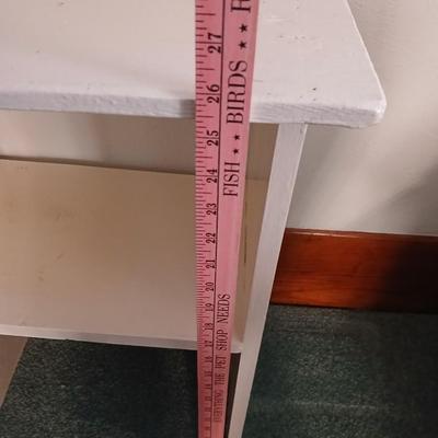 Small white table with a shelf and a wall shelf unit with many cubbies