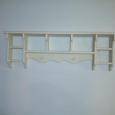 Small white table with a shelf and a wall shelf unit with many cubbies