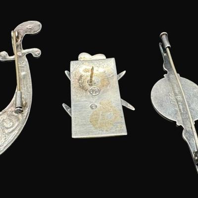 Sale Photo Thumbnail #629: **WIRE TRANSFER IS REQUIRED IF SHIPPED.** [25.92g] Includes a Danish ship design pin, a Far Fetched Co. pin with gold vermeil, and an Arabic sword pin. Total of three pieces. There is age related wear to the sword pin. Measurement of largest: 2.5”. Silv