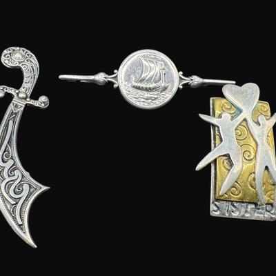 Sale Photo Thumbnail #628: **WIRE TRANSFER IS REQUIRED IF SHIPPED.** [25.92g] Includes a Danish ship design pin, a Far Fetched Co. pin with gold vermeil, and an Arabic sword pin. Total of three pieces. There is age related wear to the sword pin. Measurement of largest: 2.5”. Silv