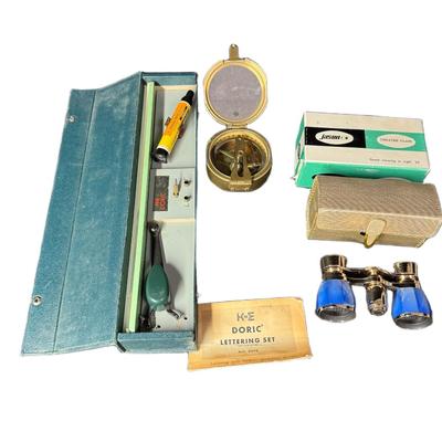 Sale Photo Thumbnail #721: Includes a Stanley London nautical brass compass, a K&E Doric lettering set, and a pair of Jason 2x opera theater glasses. Total of three pieces. Not tested. Measurement of largest: 12.5”. [CS]