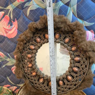 Light colored wicker baskets and a vintage macrame and beaded mirror with a frosted scene