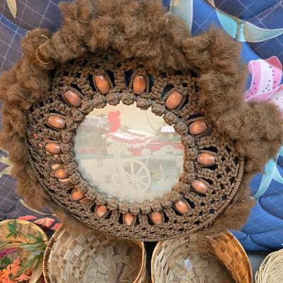 Light colored wicker baskets and a vintage macrame and beaded mirror with a frosted scene