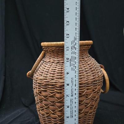 A hammered brass vase with two wicker basket vases