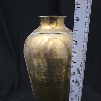 A hammered brass vase with two wicker basket vases
