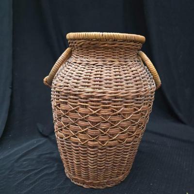 A hammered brass vase with two wicker basket vases