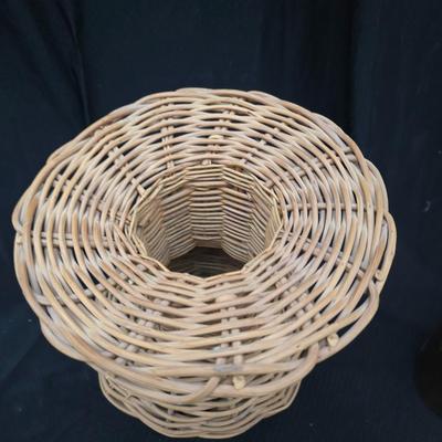 A hammered brass vase with two wicker basket vases