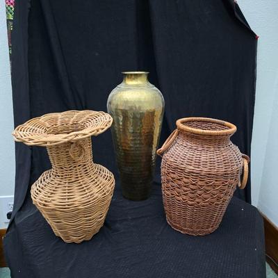 A hammered brass vase with two wicker basket vases