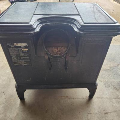 Sale Photo Thumbnail #5: Hearthstone cast iron wood-burning stove featuring decorative soapstone panels. The stove has a viewing window on the front door, a top-loading soapstone panel design, and is freestanding. Designed for efficient heating and aesthetic appeal with intricate