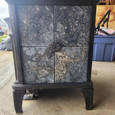 Sale Photo Thumbnail #4: Hearthstone cast iron wood-burning stove featuring decorative soapstone panels. The stove has a viewing window on the front door, a top-loading soapstone panel design, and is freestanding. Designed for efficient heating and aesthetic appeal with intricate