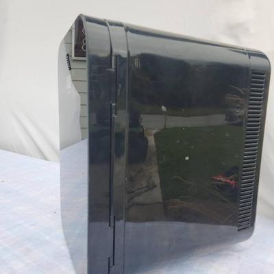 Sale Photo Thumbnail #63: Ergo compact mini electric refrigerator with a sleek black exterior and reflective front panel. Features two internal shelves and a door basket for efficient storage. Suitable for cooling small food items or beverages. Compact design and lightweight struc