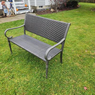 Sale Photo Thumbnail #48: Metal-framed outdoor bench featuring a woven synthetic material for the seat and backrest. Equipped with armrests and curved legs, the bench is designed for durability and outdoor use. The woven pattern provides comfort and adds aesthetic detail. Suitable