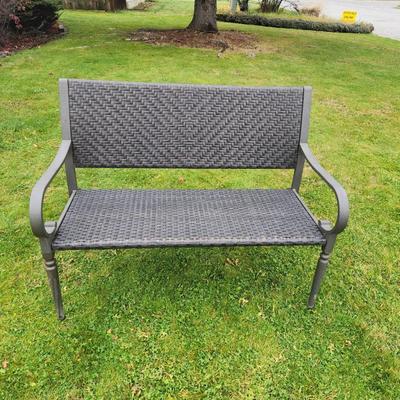 Sale Photo Thumbnail #47: Metal-framed outdoor bench featuring a woven synthetic material for the seat and backrest. Equipped with armrests and curved legs, the bench is designed for durability and outdoor use. The woven pattern provides comfort and adds aesthetic detail. Suitable