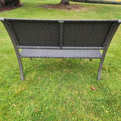 Sale Photo Thumbnail #49: Metal-framed outdoor bench featuring a woven synthetic material for the seat and backrest. Equipped with armrests and curved legs, the bench is designed for durability and outdoor use. The woven pattern provides comfort and adds aesthetic detail. Suitable
