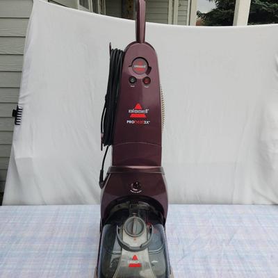 Sale Photo Thumbnail #100: Bissell ProHeat 2X upright carpet cleaner featuring 12 rows of dual DirtLifter power brushes for deep cleaning. Includes a built-in hose and tool storage for accessories. Designed for effective carpet and upholstery cleaning with easy portability. In used