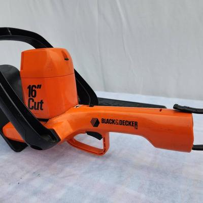 Sale Photo Thumbnail #120: Black & Decker 16-inch electric hedge trimmer featuring an orange body with a black handle. Includes a protective blade cover. Corded design (cord not included). Model number and year of manufacture are not specified. Appears to be in used condition.