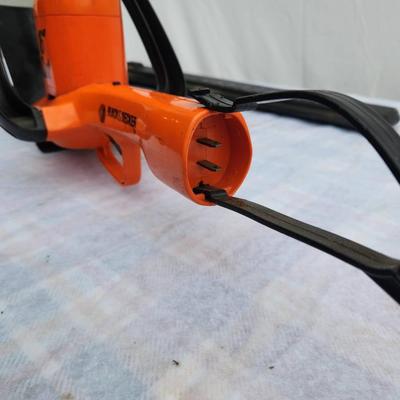 Sale Photo Thumbnail #121: Black & Decker 16-inch electric hedge trimmer featuring an orange body with a black handle. Includes a protective blade cover. Corded design (cord not included). Model number and year of manufacture are not specified. Appears to be in used condition.