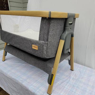 Sale Photo Thumbnail #72: AMKE baby bassinet with a stylish wooden frame and soft mesh siding for breathability and visibility. Includes an accompanying mattress and fitted sheet. Comes with a convenient carrying bag for portability. Designed for stability and easy assembly. Minim