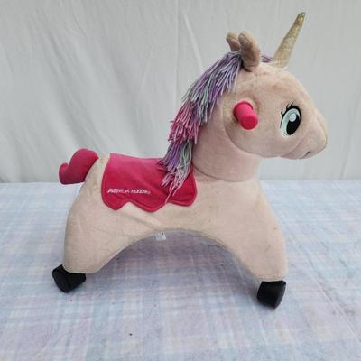 Sale Photo Thumbnail #94: Plush unicorn rocker featuring a beige body with a pink saddle detail and purple hair. Includes a golden horn, pink ears, and green eyes for a playful design. Equipped with four sturdy wheels and two pink handles, it provides both rocking and mobility fun