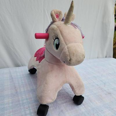 Sale Photo Thumbnail #93: Plush unicorn rocker featuring a beige body with a pink saddle detail and purple hair. Includes a golden horn, pink ears, and green eyes for a playful design. Equipped with four sturdy wheels and two pink handles, it provides both rocking and mobility fun