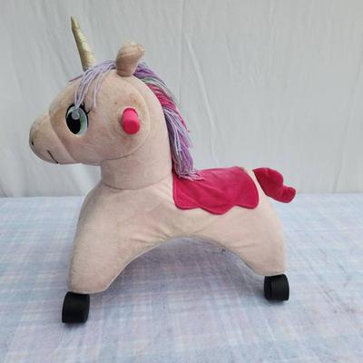 Sale Photo Thumbnail #92: Plush unicorn rocker featuring a beige body with a pink saddle detail and purple hair. Includes a golden horn, pink ears, and green eyes for a playful design. Equipped with four sturdy wheels and two pink handles, it provides both rocking and mobility fun