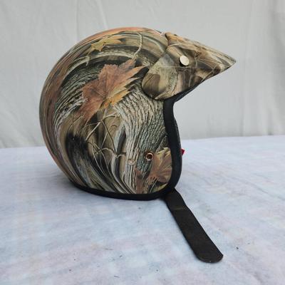 Sale Photo Thumbnail #144: AFX half helmet featuring a camouflage pattern with autumn leaves. Includes an adjustable chin strap with quick-release buckle for secure fitting. Lightweight and designed for safety with padding along the edge. Ideal for outdoor enthusiasts and motorcycl