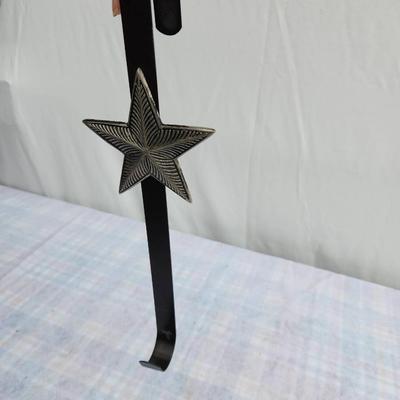 Sale Photo Thumbnail #159: Black metal door hanger featuring a star-shaped decorative element with intricate detailing. The hanger has a hooked top and bottom design, suitable for hanging items on doors. Constructed from sturdy metal with a durable finish. Overall condition is good