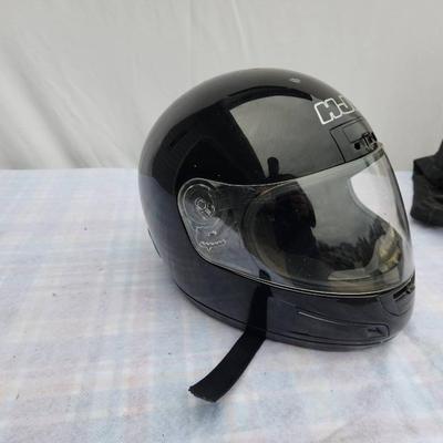 Sale Photo Thumbnail #169: HJC full-face motorcycle helmet in black color featuring a transparent visor. Shows visible signs of wear with scratches present on the surface. Equipped with an adjustable strap for a secure fit. Includes branding on the front. Condition consistent with 