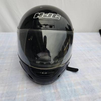 Sale Photo Thumbnail #167: HJC full-face motorcycle helmet in black color featuring a transparent visor. Shows visible signs of wear with scratches present on the surface. Equipped with an adjustable strap for a secure fit. Includes branding on the front. Condition consistent with 