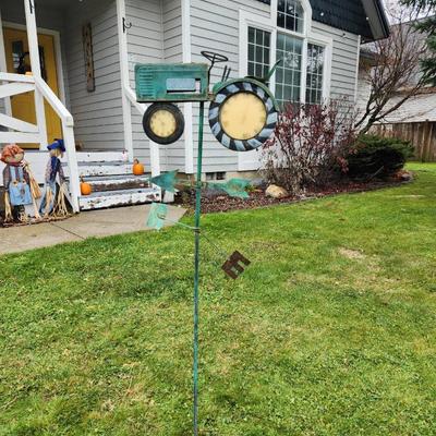 Sale Photo Thumbnail #187: Decorative metal weathervane featuring a tractor motif with clock faces integrated into the front and rear wheels. The piece is weathered for a rustic look and includes directional markers for North, East, South, and West. Designed for outdoor installatio