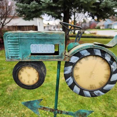 Sale Photo Thumbnail #188: Decorative metal weathervane featuring a tractor motif with clock faces integrated into the front and rear wheels. The piece is weathered for a rustic look and includes directional markers for North, East, South, and West. Designed for outdoor installatio