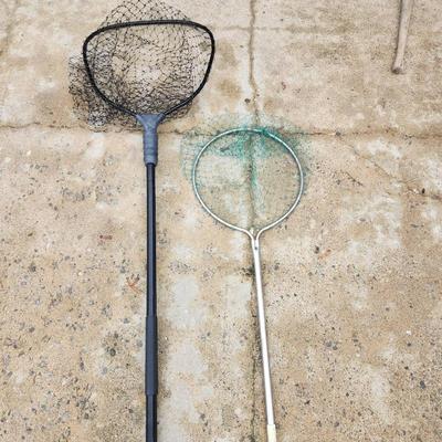 Sale Photo Thumbnail #189: Two fishing nets, featuring one net with a black plastic handle and frame, and another with a metal frame and green netting. Both nets are designed for outdoor use, suitable for fishing or catching small aquatic creatures. Condition shows some wear consis