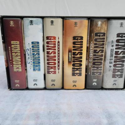 Sale Photo Thumbnail #204: Gunsmoke 65th Anniversary Collection, featuring the complete series on DVD. The set includes a boxed collection with multiple DVDs across multiple cases, showcasing iconic artwork related to the series. Packed with timeless episodes, this set is a must-ha