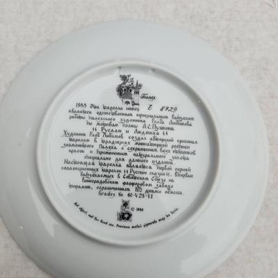 Sale Photo Thumbnail #214: Russian hand-painted lacquerware plate featuring a vibrant fairy tale scene with a horse and castle motif. The reverse side includes inscriptions in Cyrillic detailing the plate's origins and theme. Accompanied by documentation, illustrations, and origina