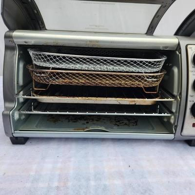Sale Photo Thumbnail #219: Hamilton Beach Easy Reach toaster oven featuring a roll-top door for convenient access. Includes adjustable temperature control knobs, a wire rack, crumb tray, and additional wire baskets. Shows signs of use with visible surface discoloration and residue.