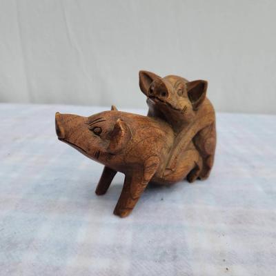 Sale Photo Thumbnail #223: A small ceramic jar labeled 'Harley money,' featuring a yellow body with a blue heart and band accent, alongside a wooden figurine of two pigs in a playful pose. The jar serves as a coin holder or decoration, while the wooden carving showcases detailed cr