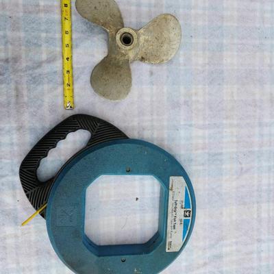 Sale Photo Thumbnail #269: One Ideal 50 ft Tuff-Grip fish tape made of S-Class non-metallic material with a steel core, featuring a durable blue housing and ergonomic hand grip. Additionally, the lot contains one 3-blade metal propeller, approximately 6 inches in diameter, suitable