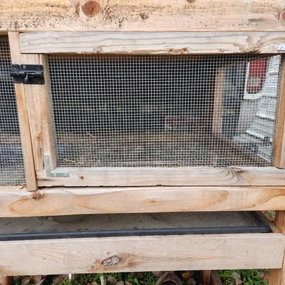 Sale Photo Thumbnail #44: A wooden quail cage with two levels, featuring wire mesh sides and bottoms for ventilation and waste management. The cage includes hinged front doors for easy access and a slanted green metal roof for weather protection. Supported by four wooden legs, it 