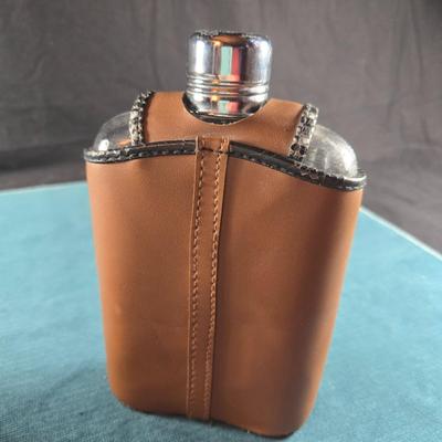 Sale Photo Thumbnail #485: This auction lot is for a Vintage Flask with Faux Leather Case. This is a useful and handsome Flask with Faux Leather Case.  The flask itself is glass and marked TRC.  The case shows wear on the black edging.  Overall in good condition.